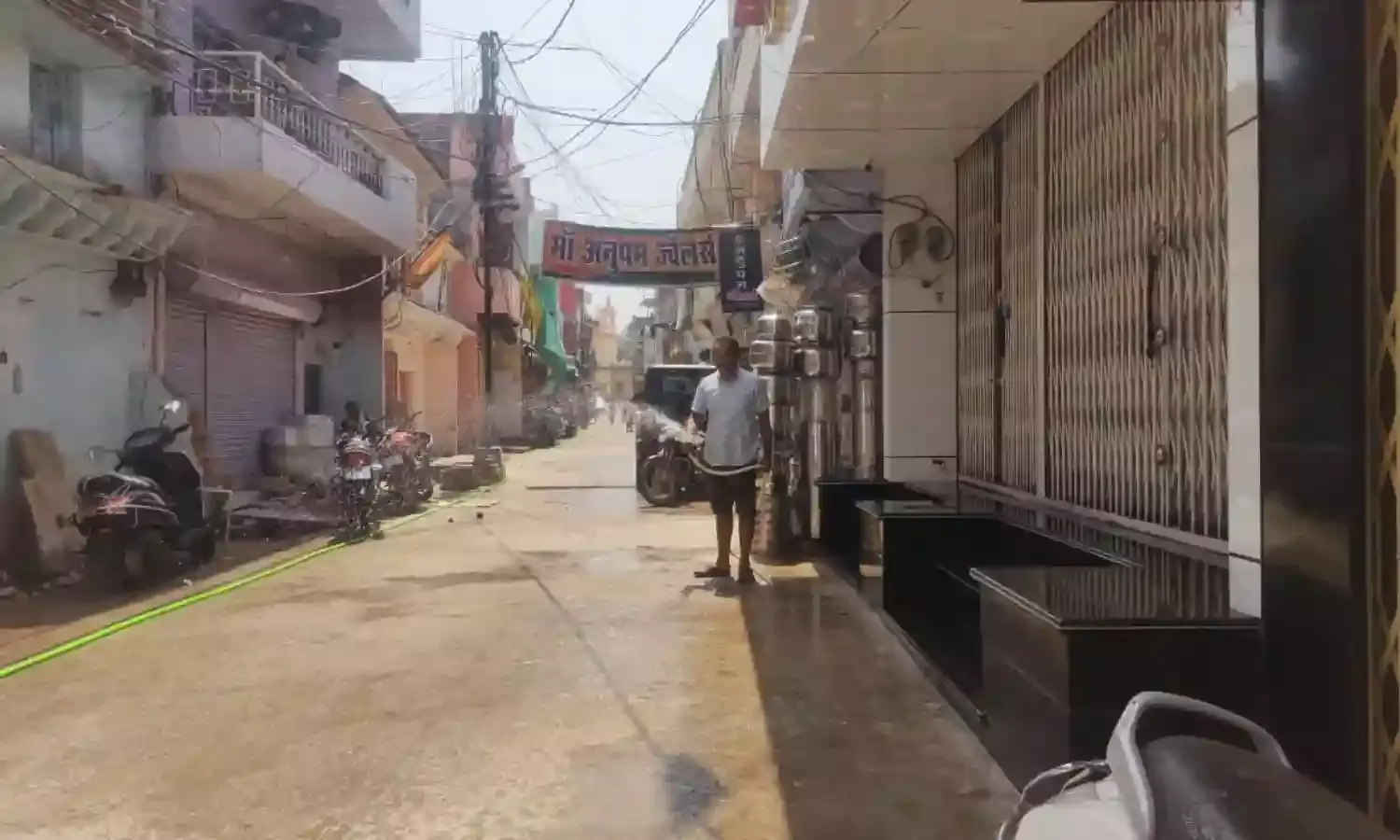 नवनिर्मित सीसी सडक की स्वयं पानी से तराई कर रहे स्थानीय निवासी