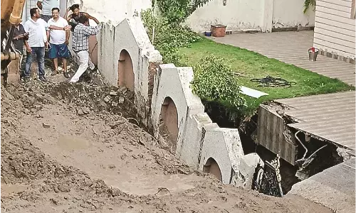 अचानक धंस गई जमीन, घर की सुरक्षा दीवार और गेट समाए - मचा हड़कंप
